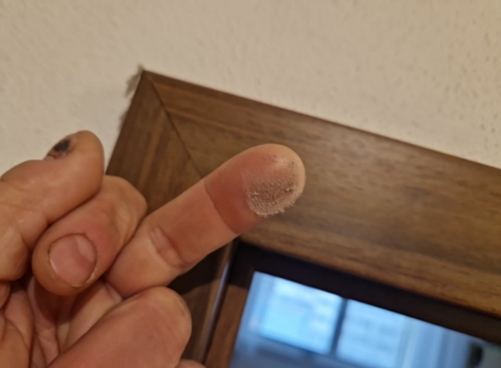 Klient na fotografii dokazuje přítomnost prachu na vrchu zárubně po požáru.